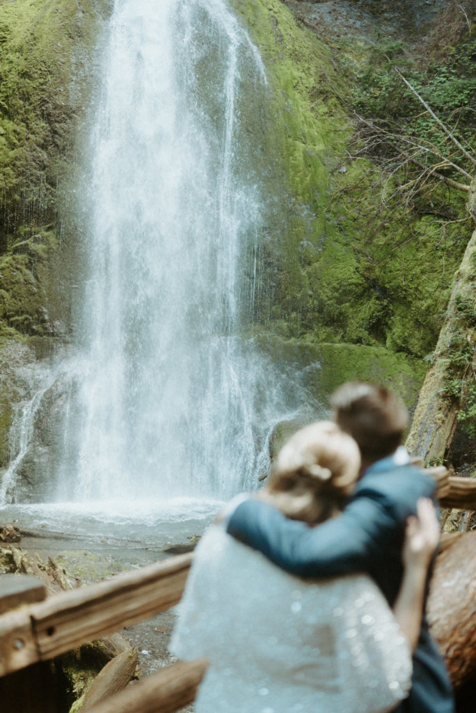 Newlywed couple in front of waterfall at Olympic National Park shot by elopement videographer Alesia Films