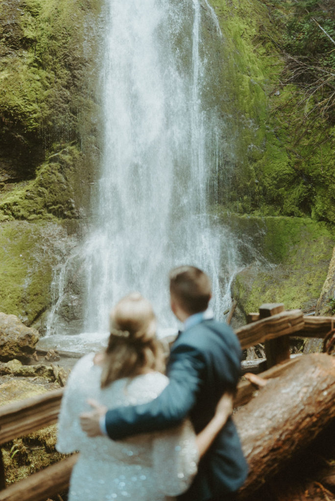 eloped couple in front of waterfall at Olympic National Park shot by elopement videographer Alesia Films