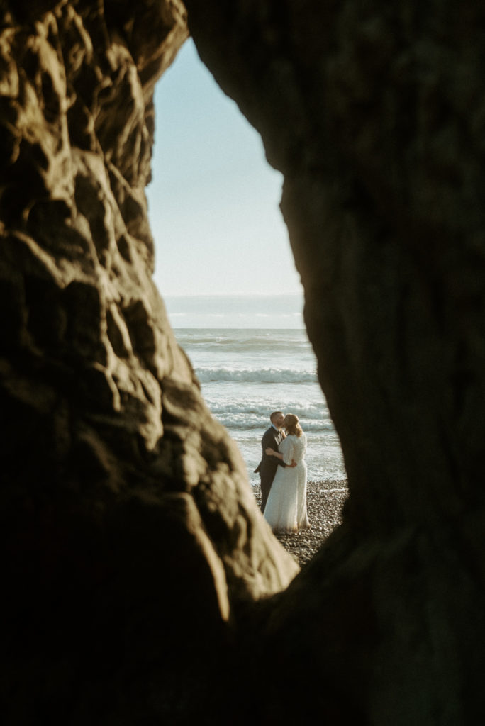 Foreground blur shot of newlywed couple at Oregon beach shot by elopement videographer Alesia Films