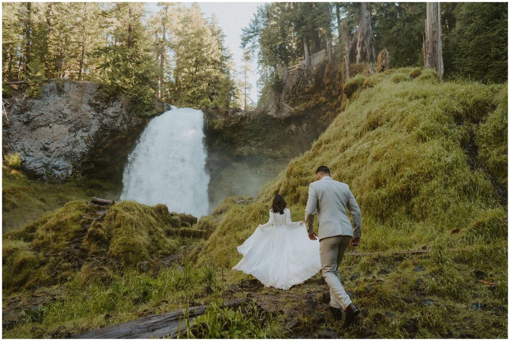 bride and groom chasing waterfall