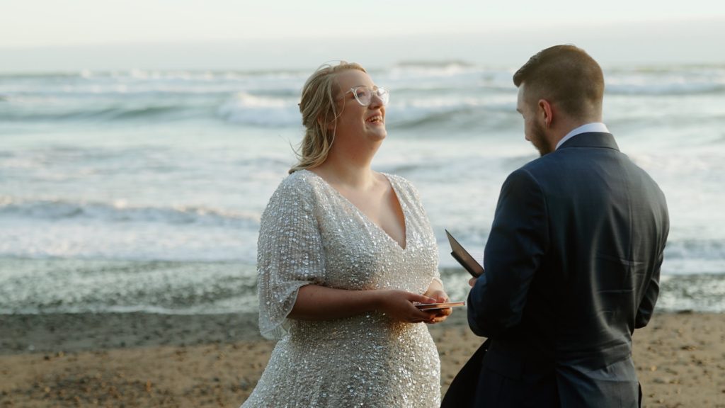 still of bride laughing during vows ceremony filmed by Oregon coast elopement videographer, Alesia Films