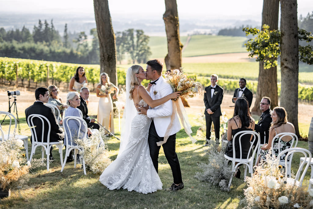 Bride and groom first kiss as newlyweds at Domaine de Broglie winery summer elopement in Dayton, Oregon