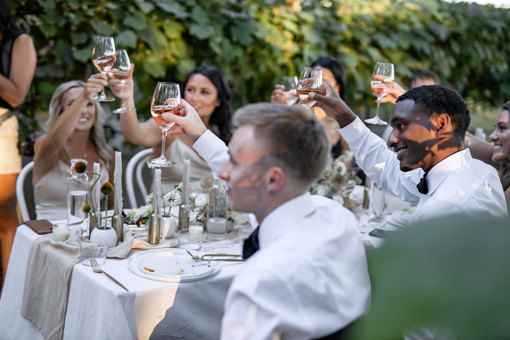 Bridal party and groomsmen cheers at dinner reception for winery summer elopement at Domaine de Broglie in Dayton, Oregon