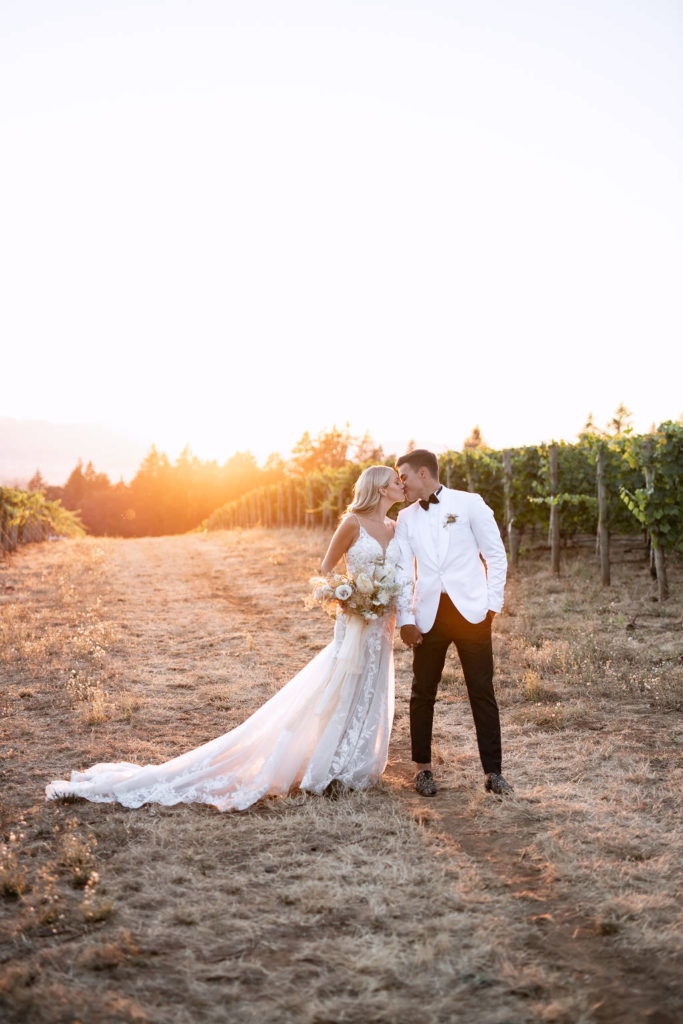 Portrait of newlyweds kiss at golden hour at Domaine de Broglie vineyard for their winery summer elopement in Dayton, Oregon
