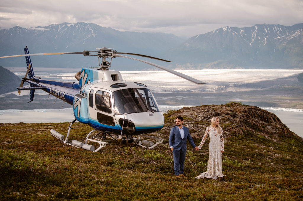 bride and groom standing in front of helicopter