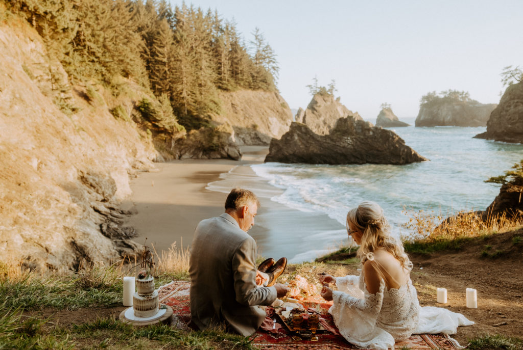 bride and groom eating at a picnic on the beach