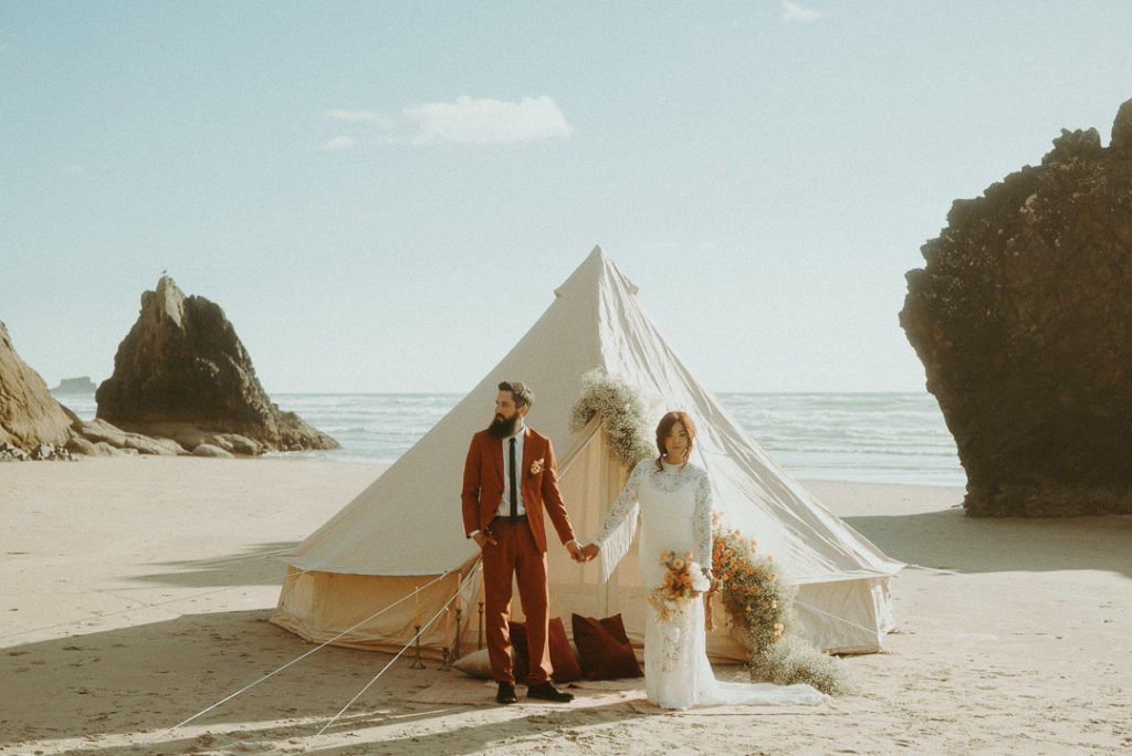 bride and groom standing in front of glamping tent