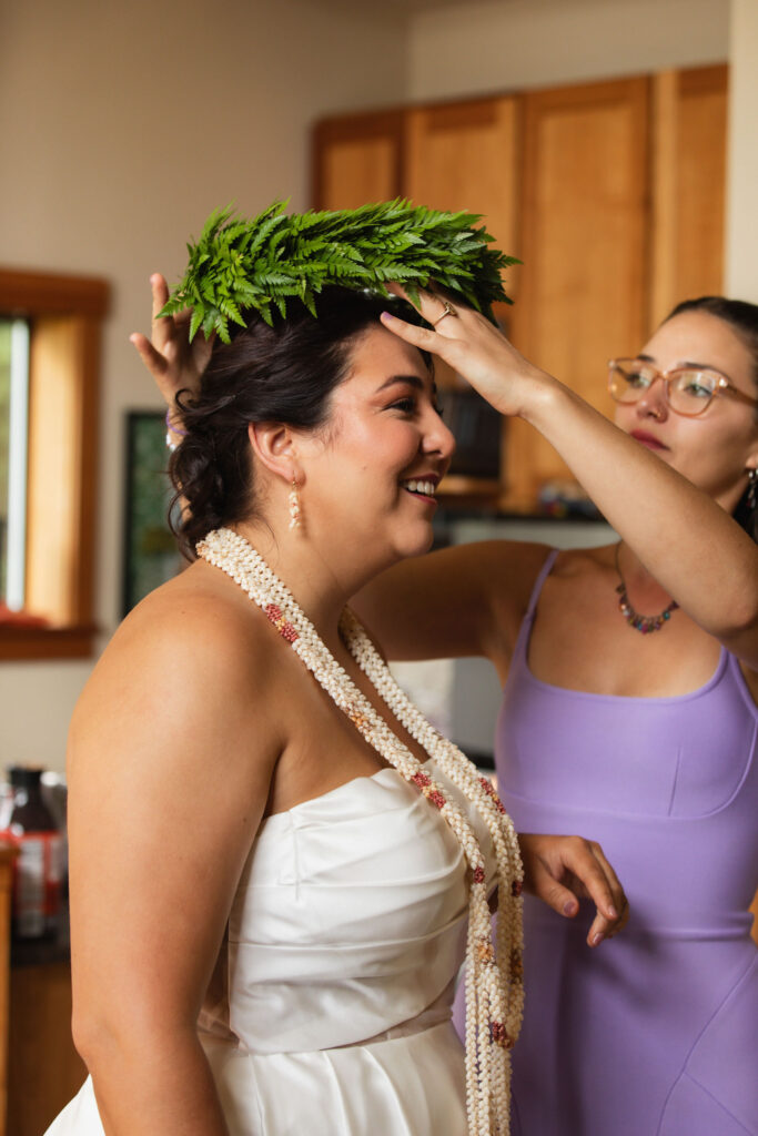 Orcas Island wedding bride putting on traditional hawaiian fern lei