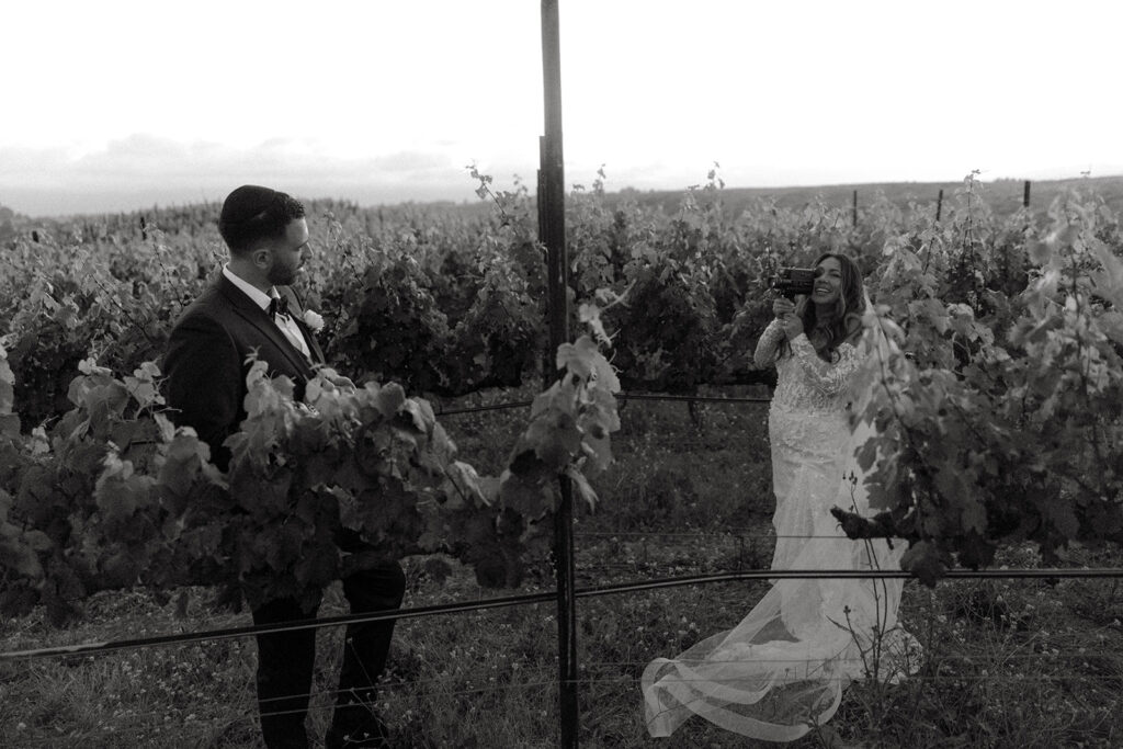 Playful black and white shot of bride and groom in Temecula vineyard