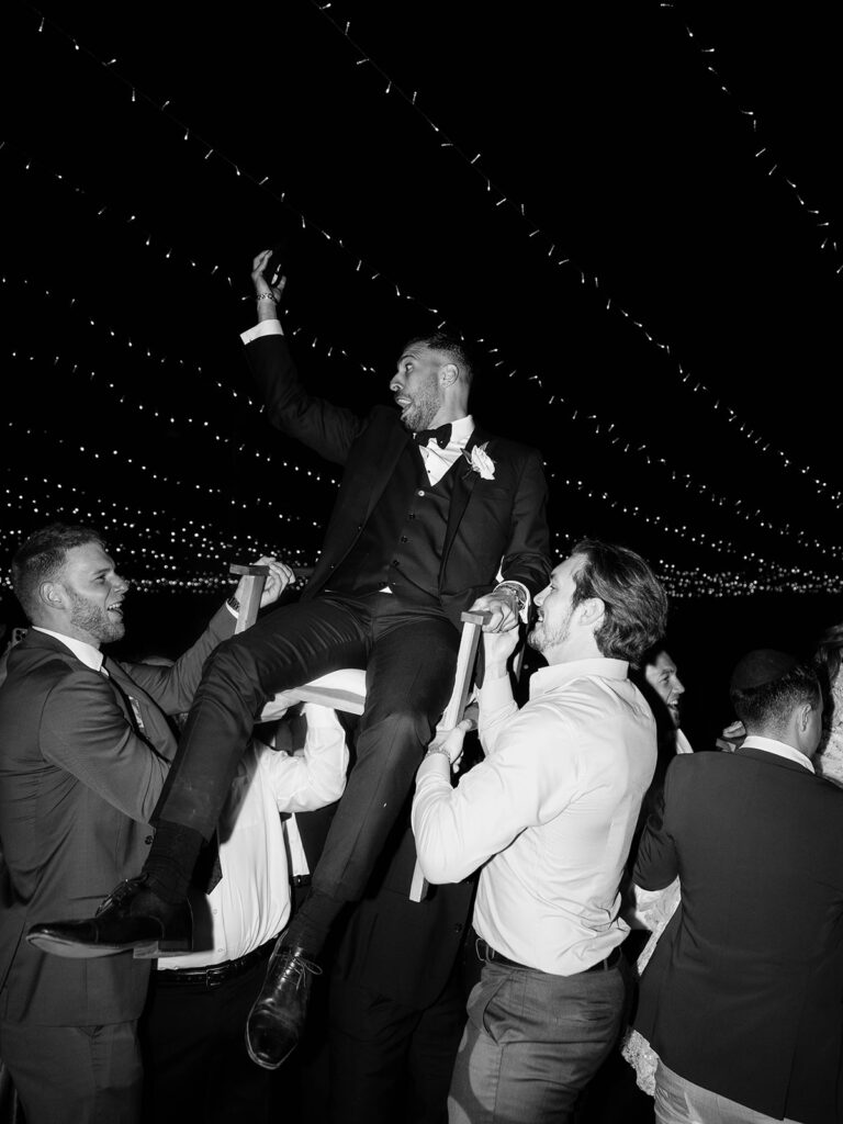 Groom being lifted on chair for hora dance during Callaway Winery wedding reception