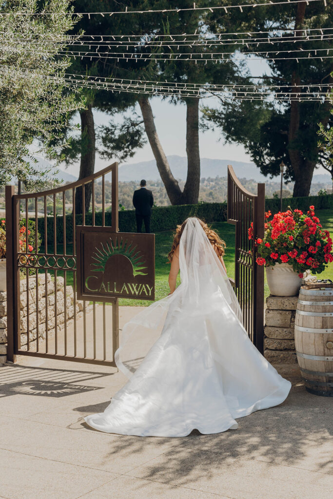 Bride approaching groom through gate for Callaway Winery wedding first look