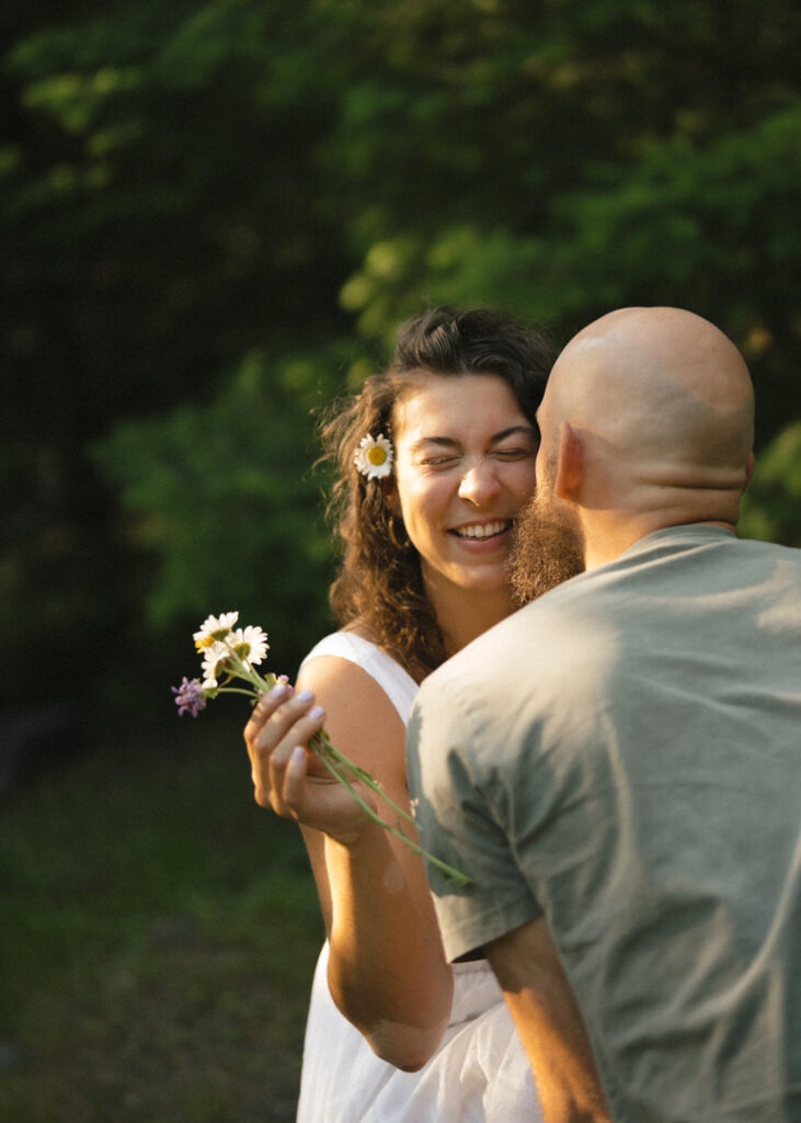 girl-holding-daisy-while-husband-kisses-her