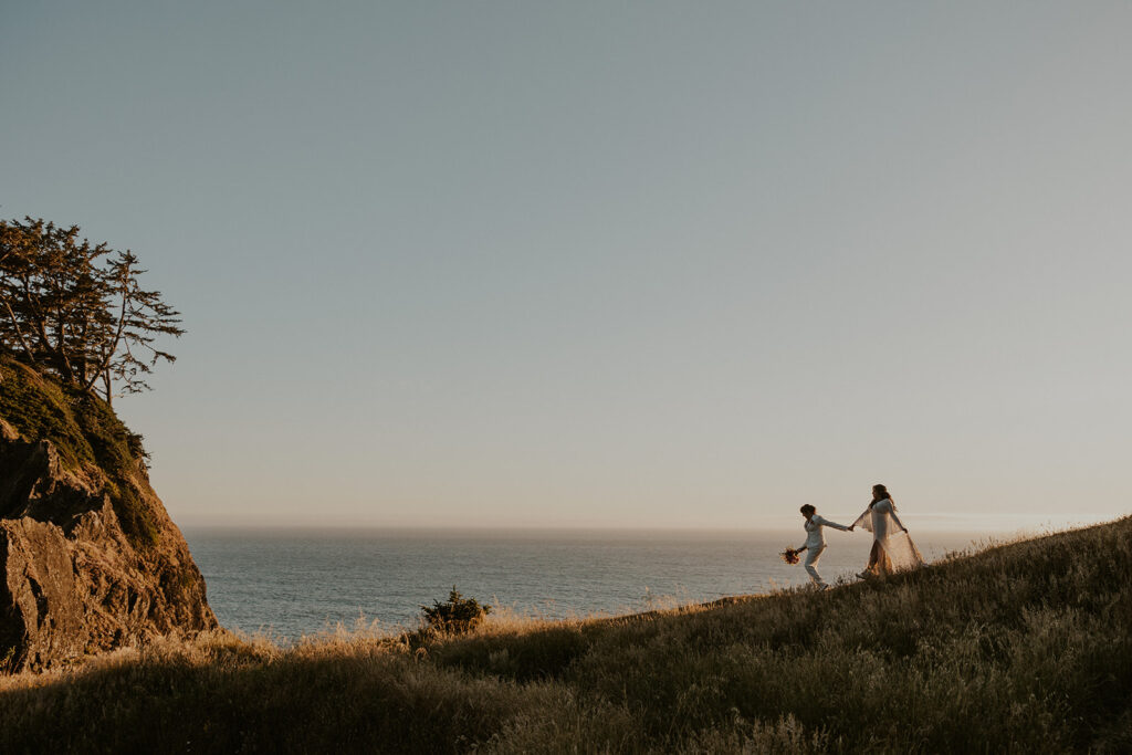 Brides walking along an ocean bluff in golden light