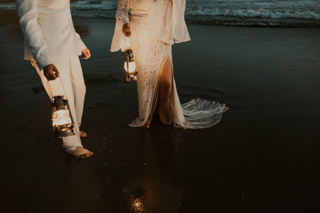 Artistic shot of brides holding lanterns as they walk along the beach