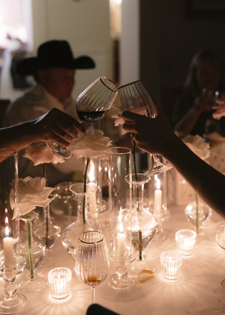 Guests cheersing with wine over candle lit reception table in Tuscany, Italy