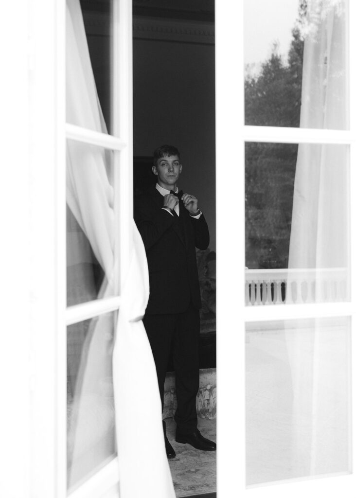 Getting ready portrait of groom through ajar french doors