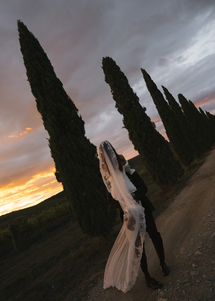 Groom lifting bride into the air during il villino farmhouse elopement sunset portrait session