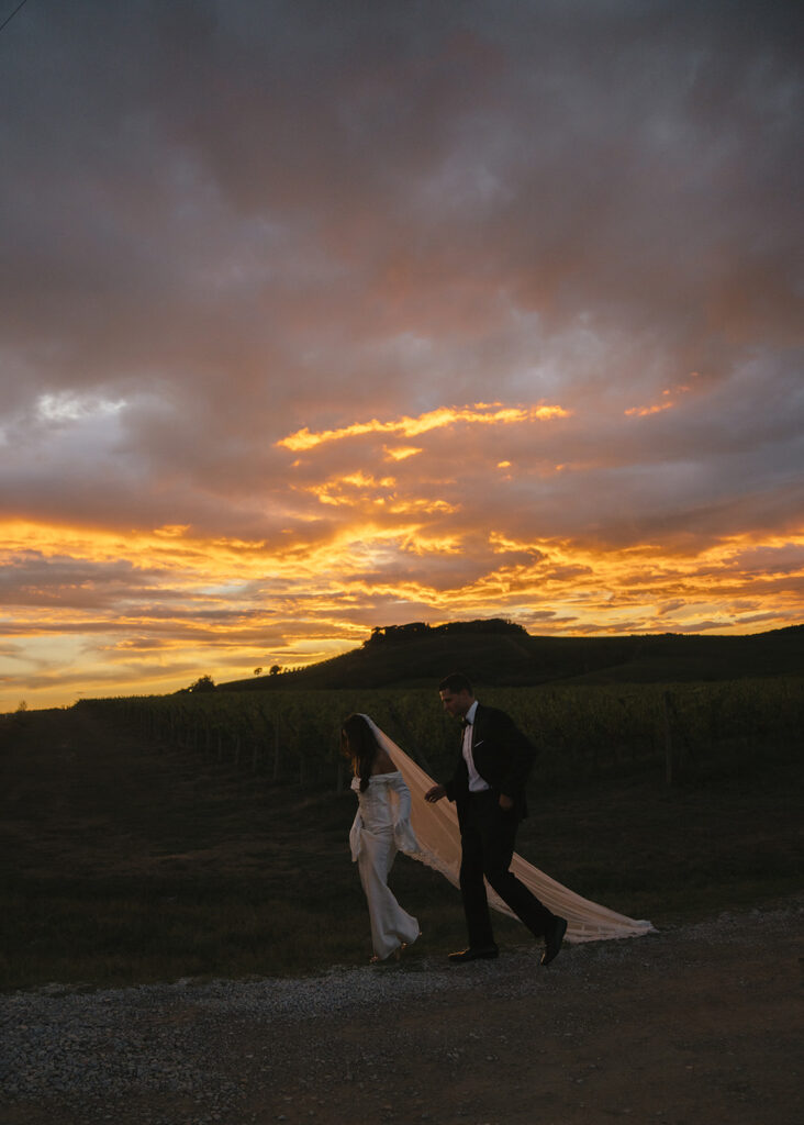 Bride and groom walking along Tuscan road at sunset