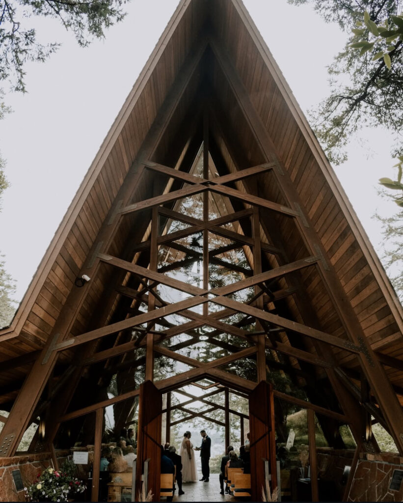 Bride and groom exchange vows inside the Capella by the Sea chapel, framed by wooden beams and natural forest light.