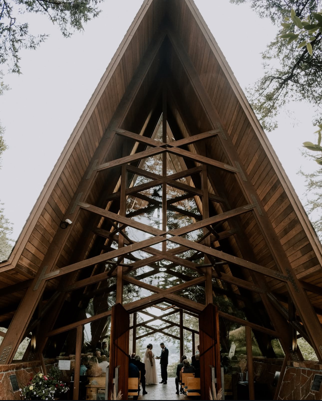 Bride and groom exchange vows inside the Capella by the Sea chapel, framed by wooden beams and natural forest light.