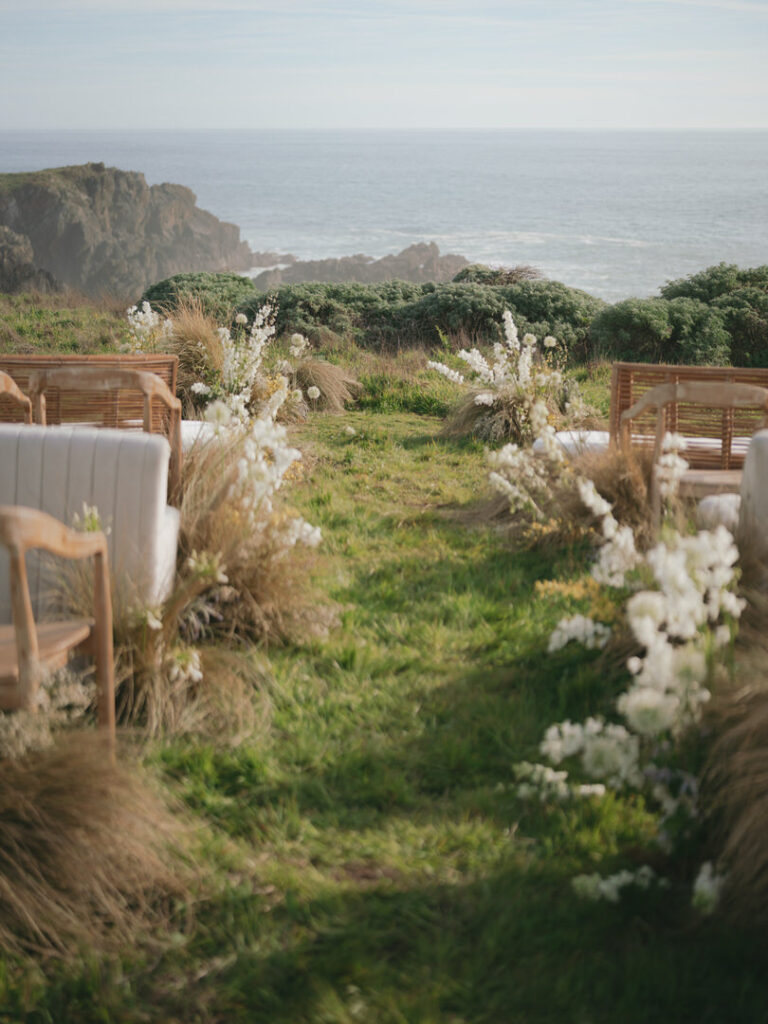Oceanfront ceremony seating styled with natural florals and grasses