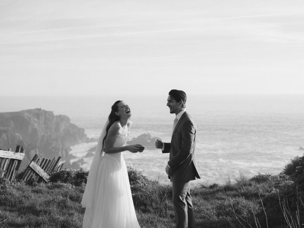Candid moment of bride and groom laughing together near the cliffside