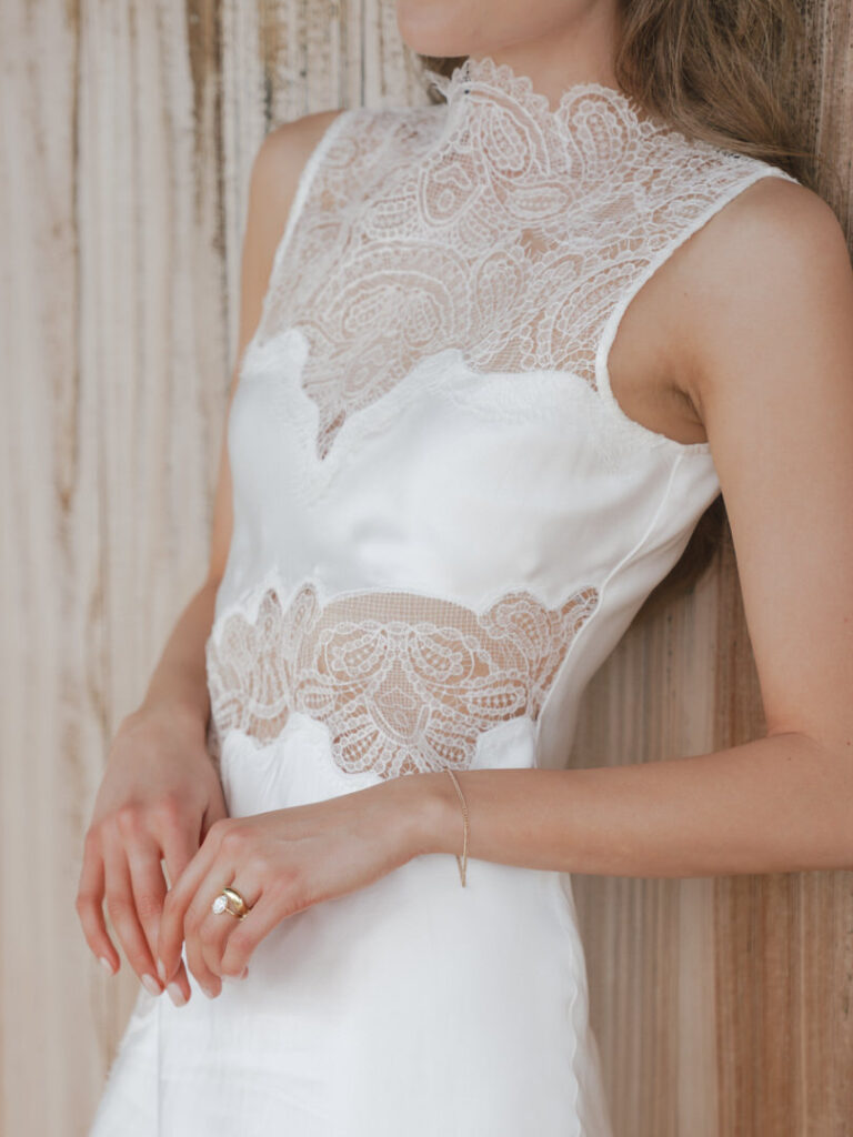 Close-up of bride’s lace wedding slip and engagement ring.