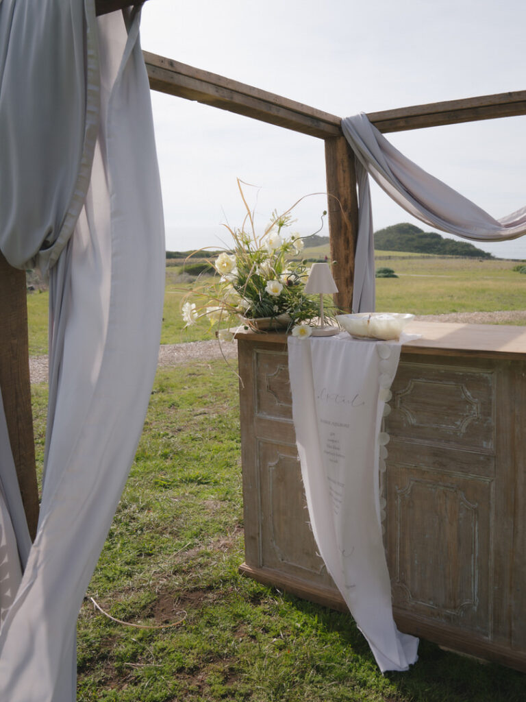 Draped outdoor bar setup with florals and signage for a Sea Ranch Lodge wedding