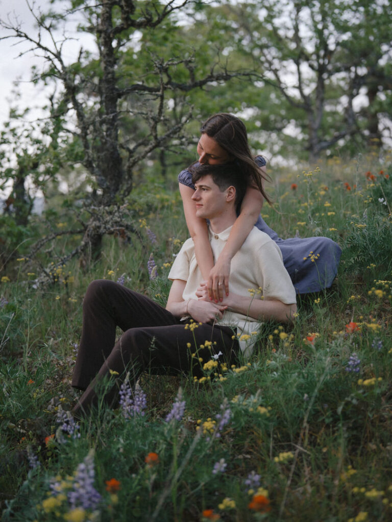 Couple leaning against hillside during their spring engagement session.